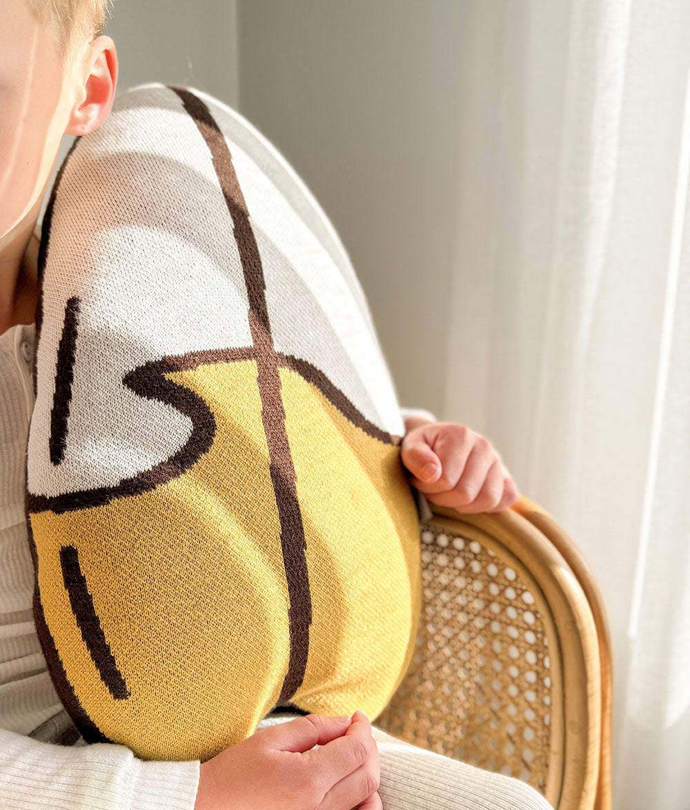 Child holding the knitted 'SURF' cushion.