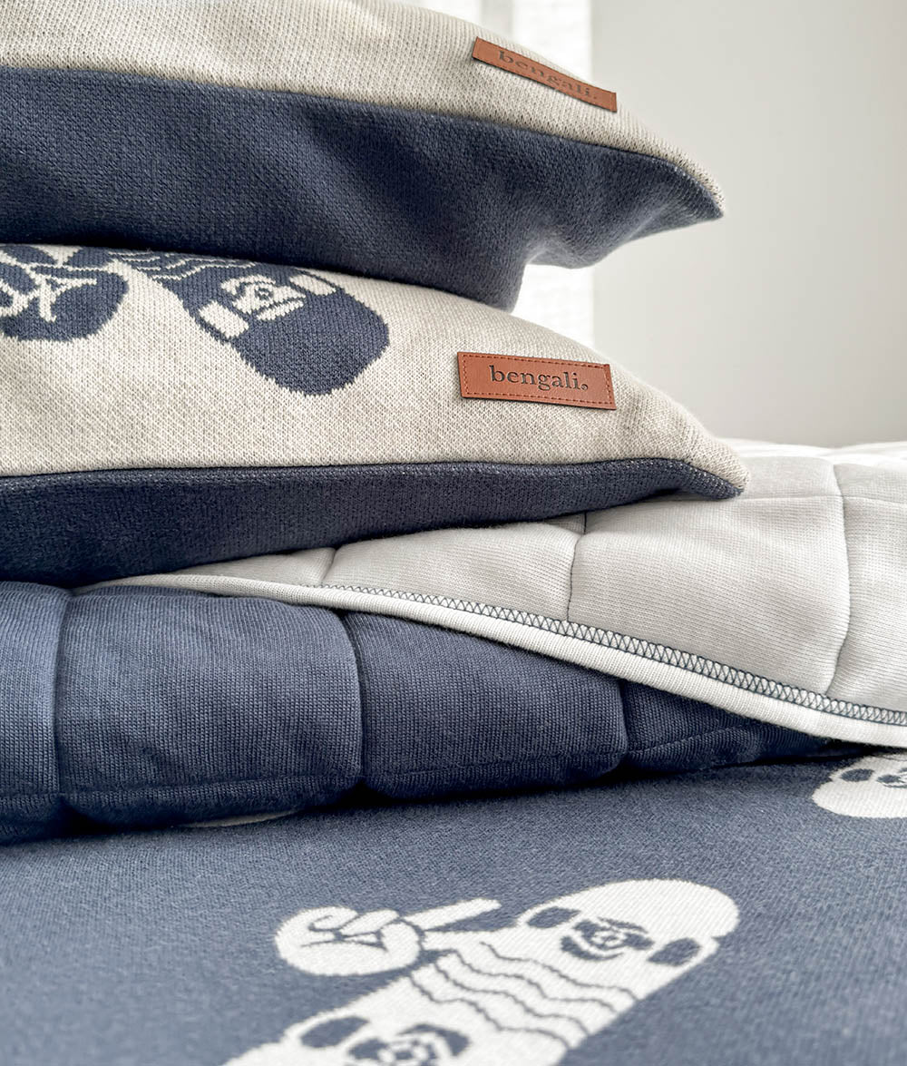Stacked Skater Life pillowcases in soft jersey cotton, featuring navy and natural colourways with ivory skateboard and peace hand prints, styled on the matching navy fitted sheet.