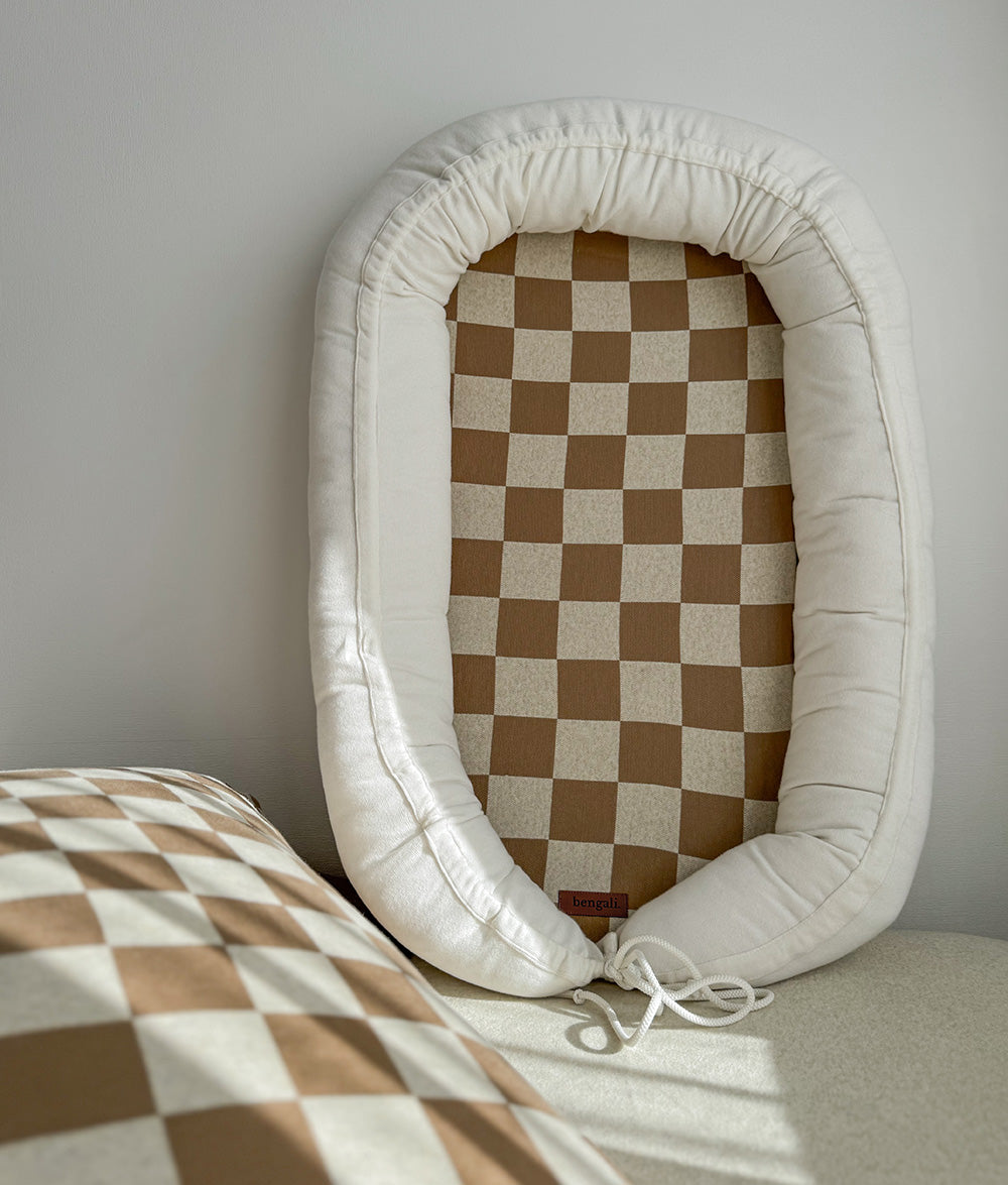 Baby lounger with ivory cushioning and khaki gingham mattress.