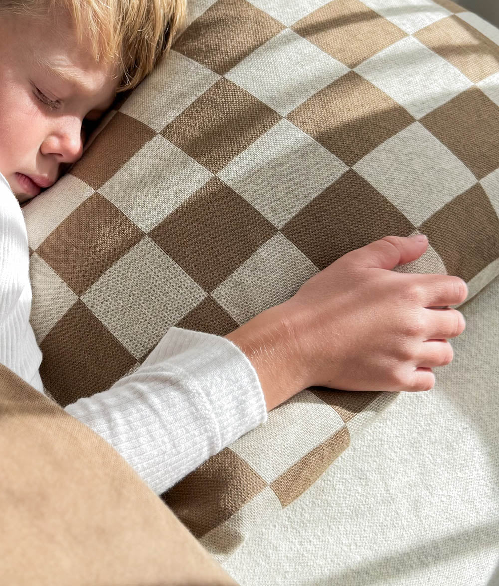 Child cuddling the Khaki Gingham Euro pillowcase.