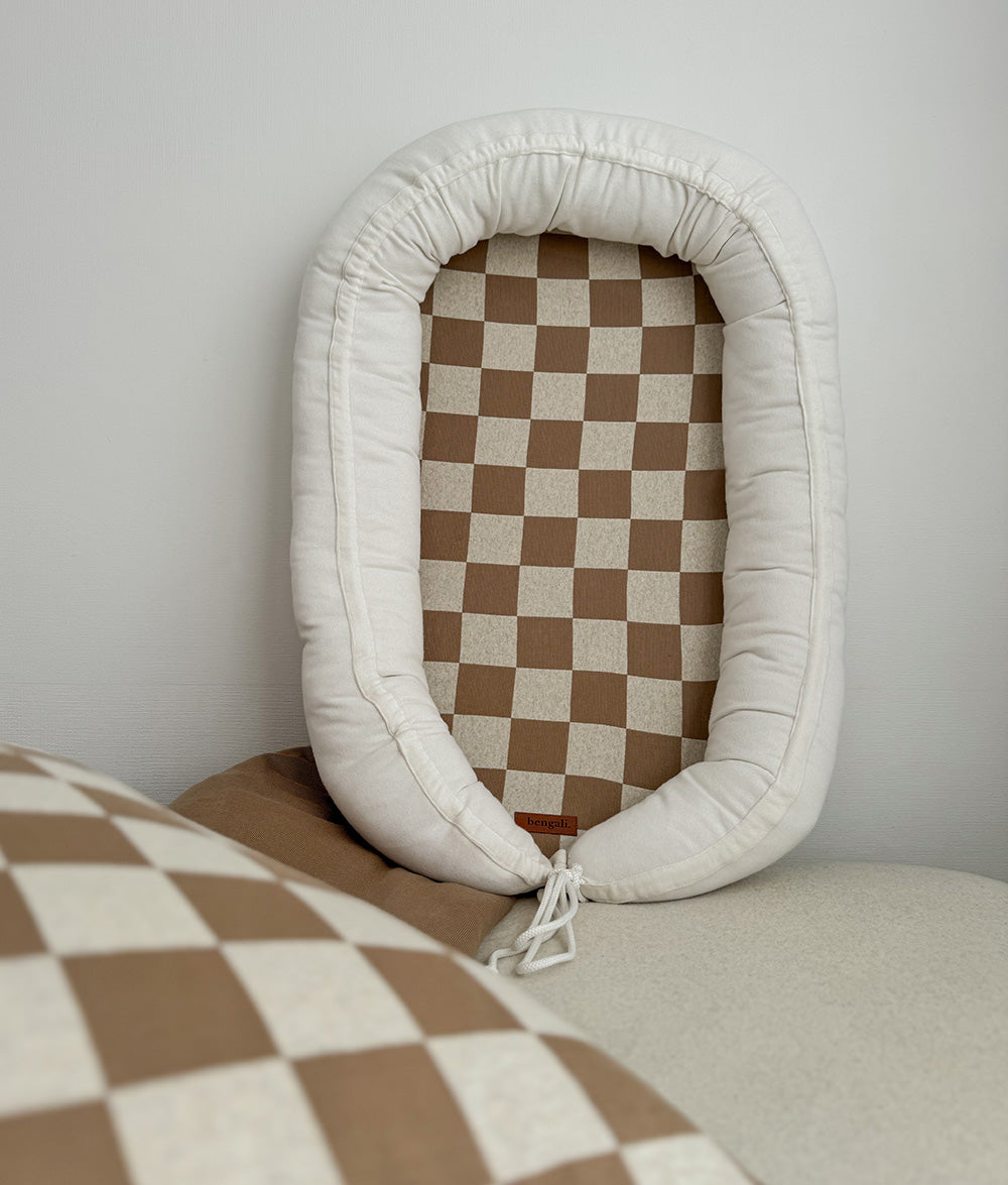 Baby lounger with ivory cushioning and khaki gingham mattress.