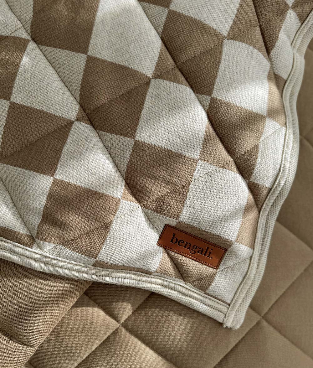 Corner detail of the Khaki Gingham quilt with Bengali Home leather label and ivory binding.