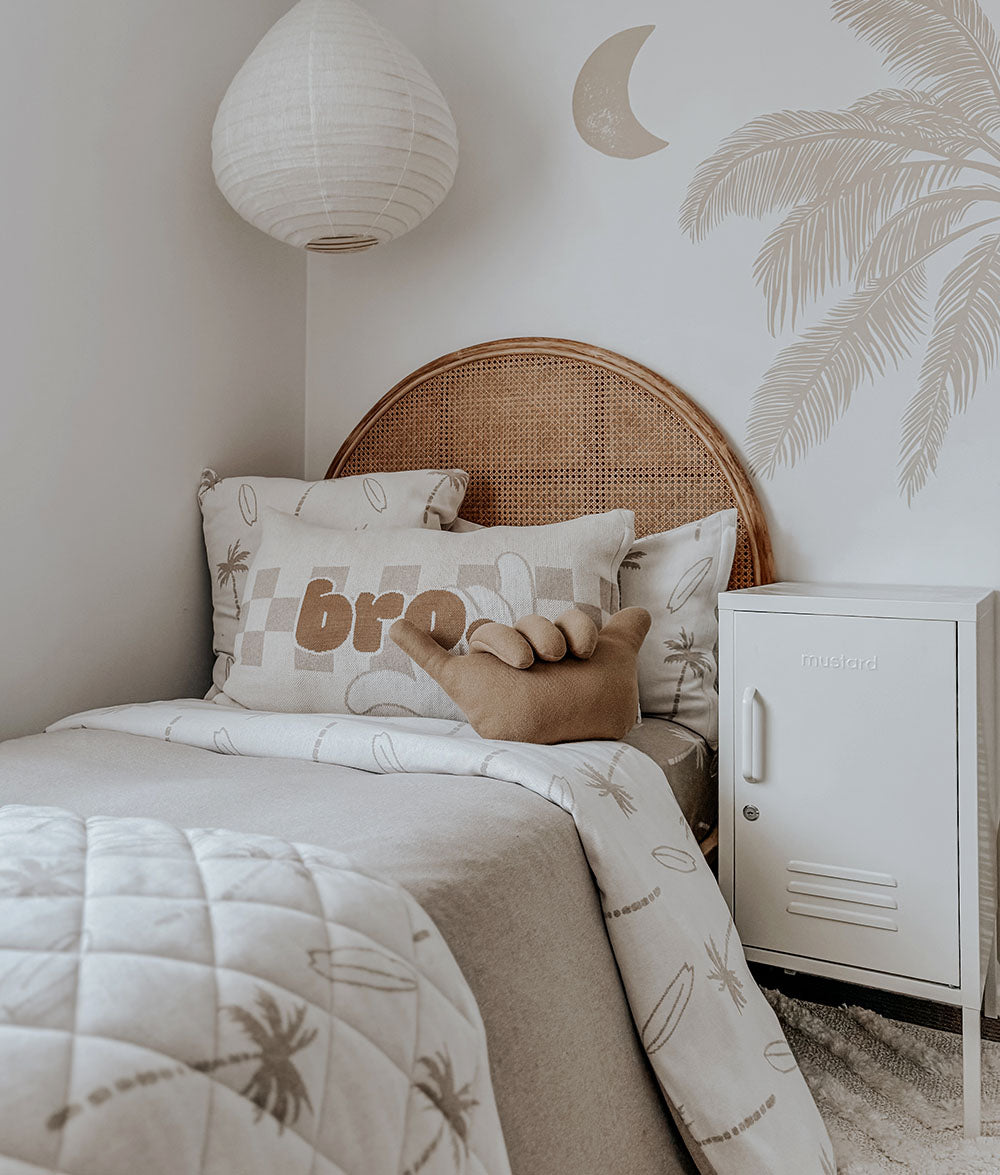 Neatly made bed with decorative pillows and a nightstand in a bedroom setting.