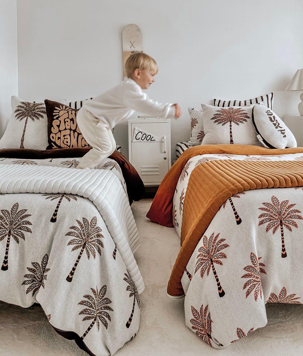 Child playing on the Peach Sundown reversible quilt and bedding.