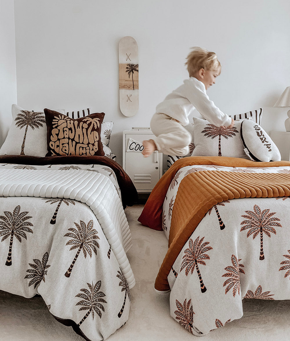 Child playing beside the Peach Sundown jersey cotton duvet cover.