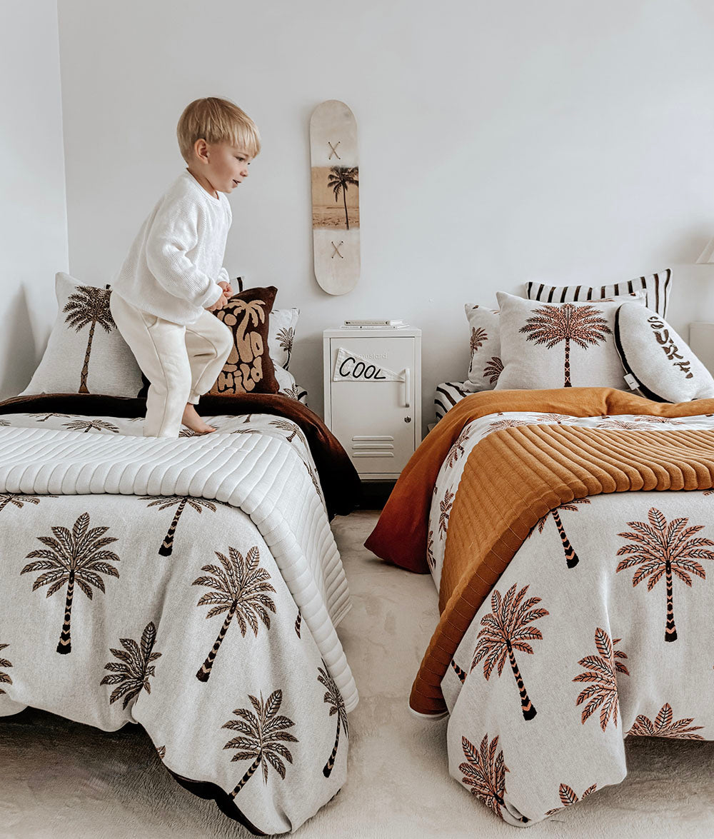 Child playing beside Sundown Stripe Euro pillowcases.