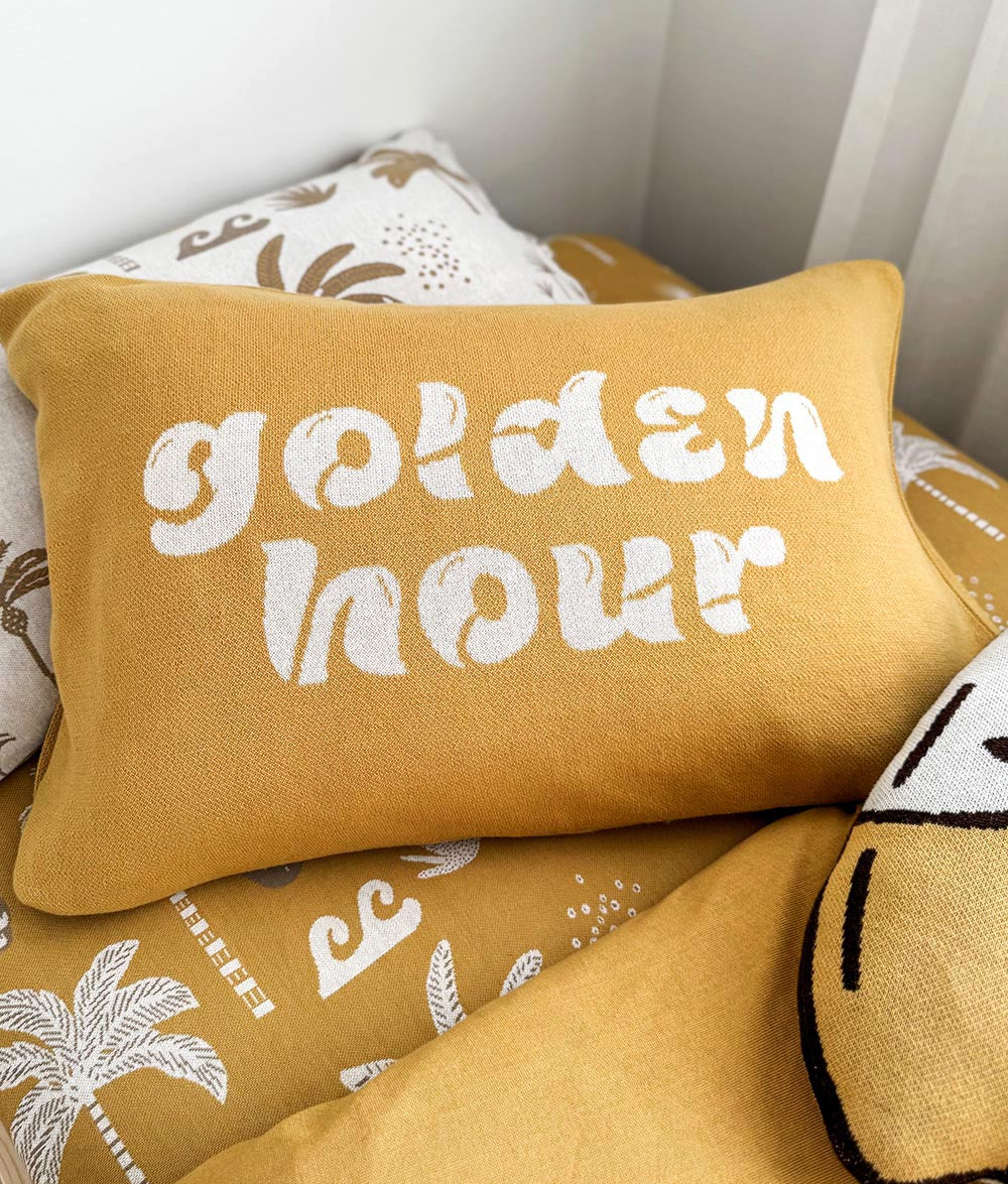 Golden Hour knitted 'golden hour' cushion layered with matching mustard bedding and surfboard cushion.