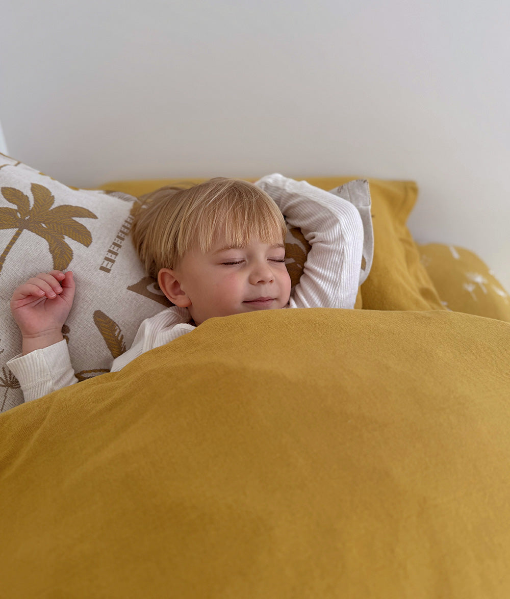 Child relaxing under the Golden Hour jersey cotton duvet cover.