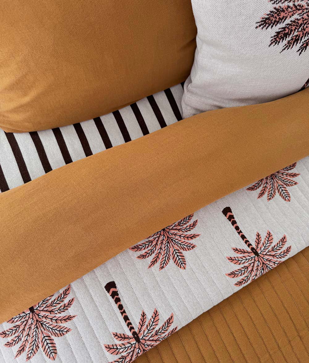 Close-up of the Peach Sundown reversible quilt with Sundown Stripe bedding.