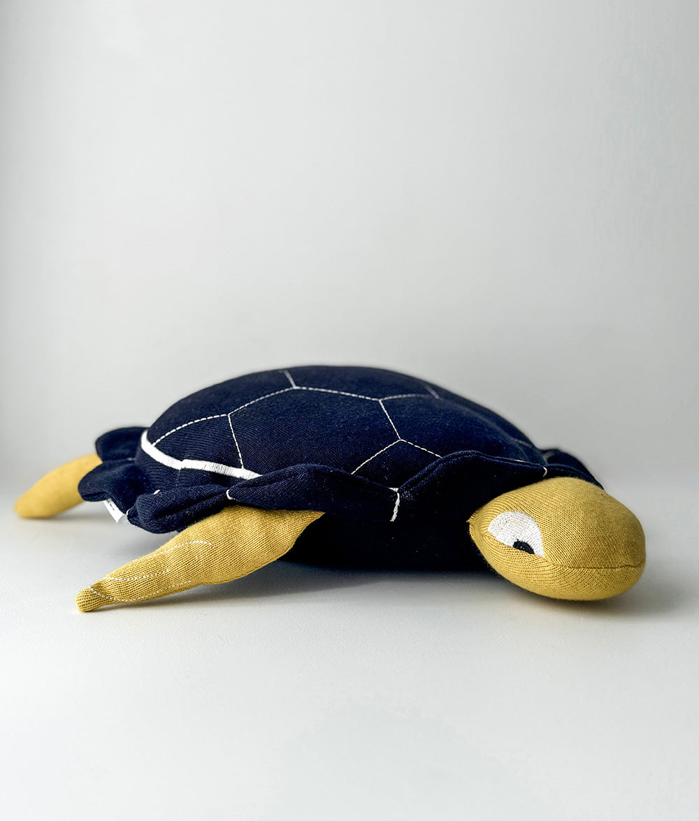Plush turtle toy with navy shell and yellow body on a light gray background