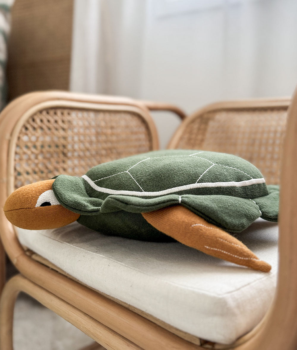 Plush turtle toy on a chair with a blurred background
