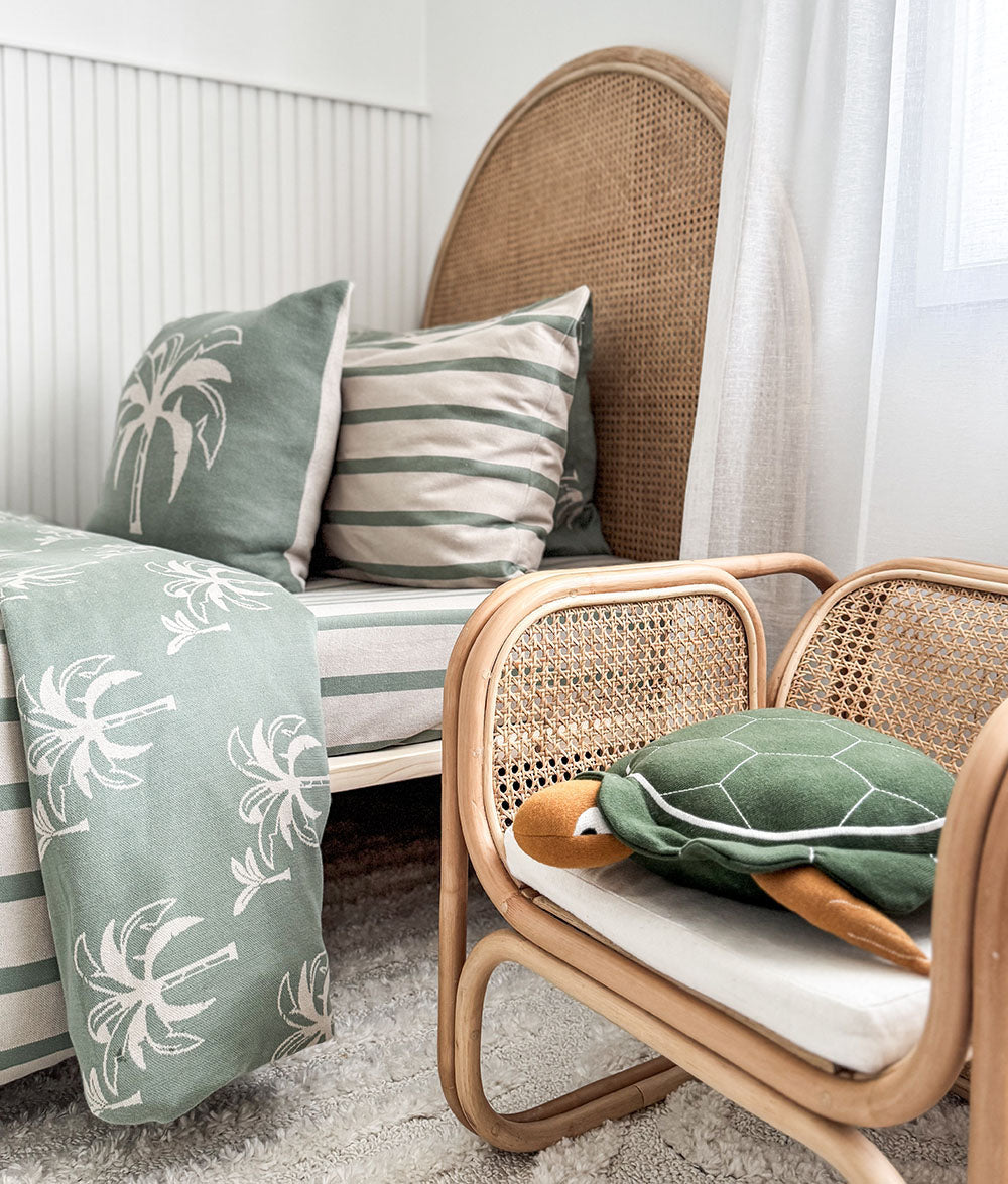 Wicker chair with cushions and a blanket in a cozy room setting