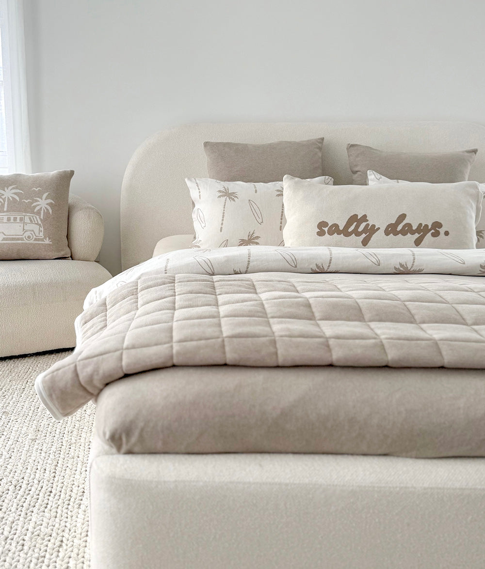 Neatly made bed with decorative pillows and a comforter in a bedroom setting.