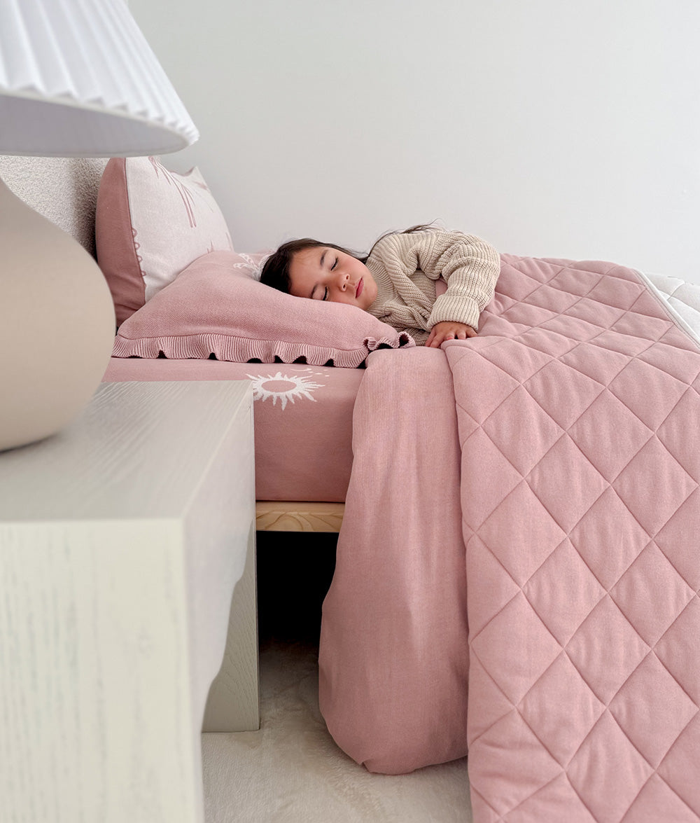 Child wrapped in the Sun Kissed reversible quilt.