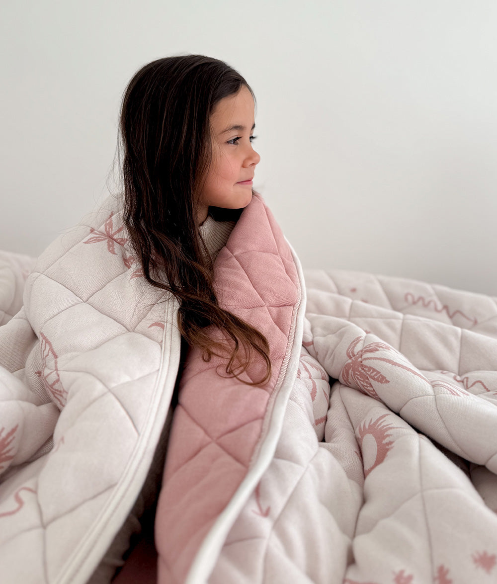 Child wrapped in the Sun Kissed reversible quilt.