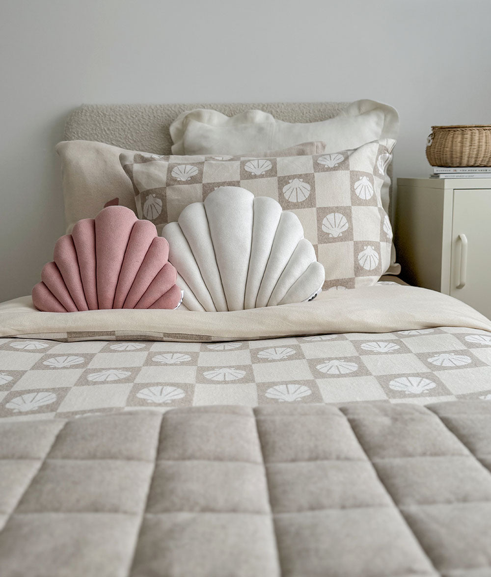 Shell-shaped cushions on a bed with a neutral color scheme