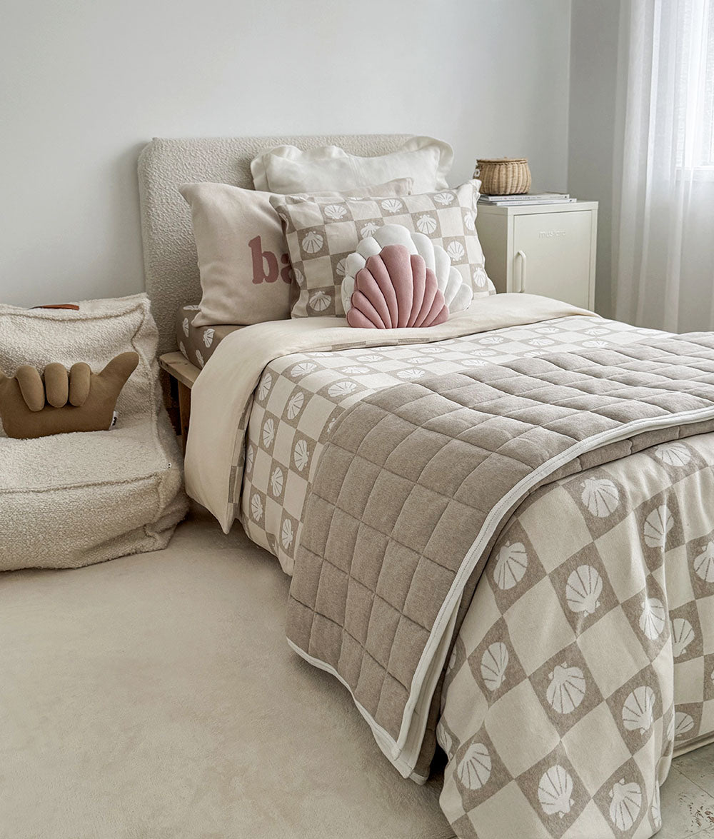 Neatly made bed with patterned comforter and pillows in a bedroom setting.