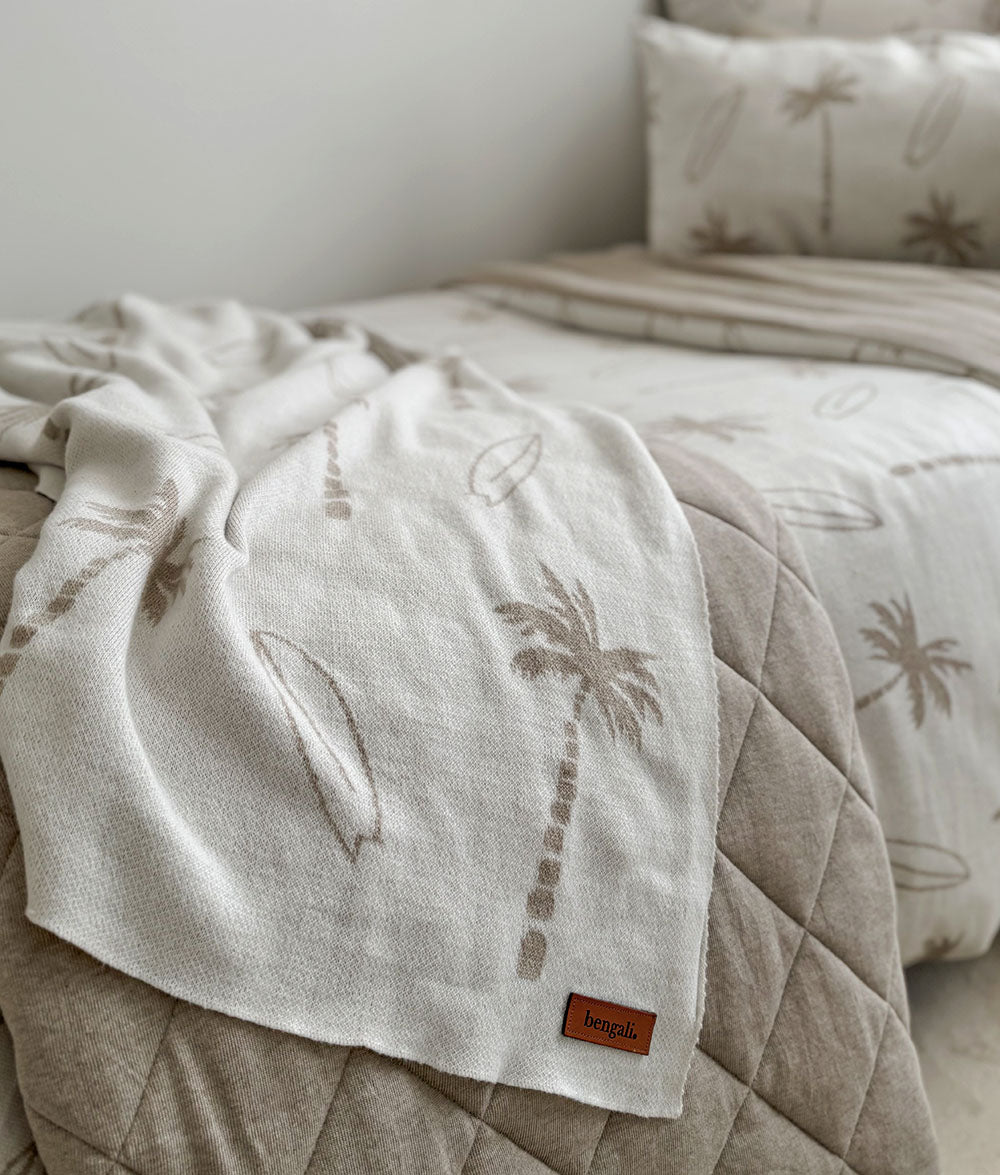 Beige quilt with palm tree design on a bed