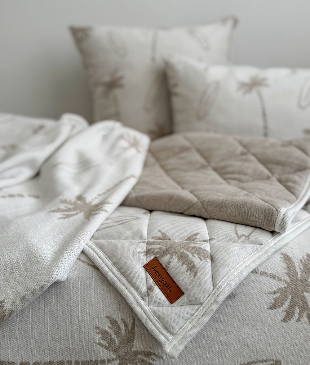 Textured blanket with a brand label on a bed with pillows