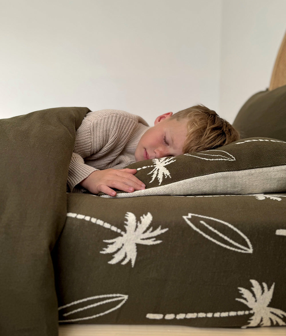 Child resting on Olive Surfing Palm bedding.