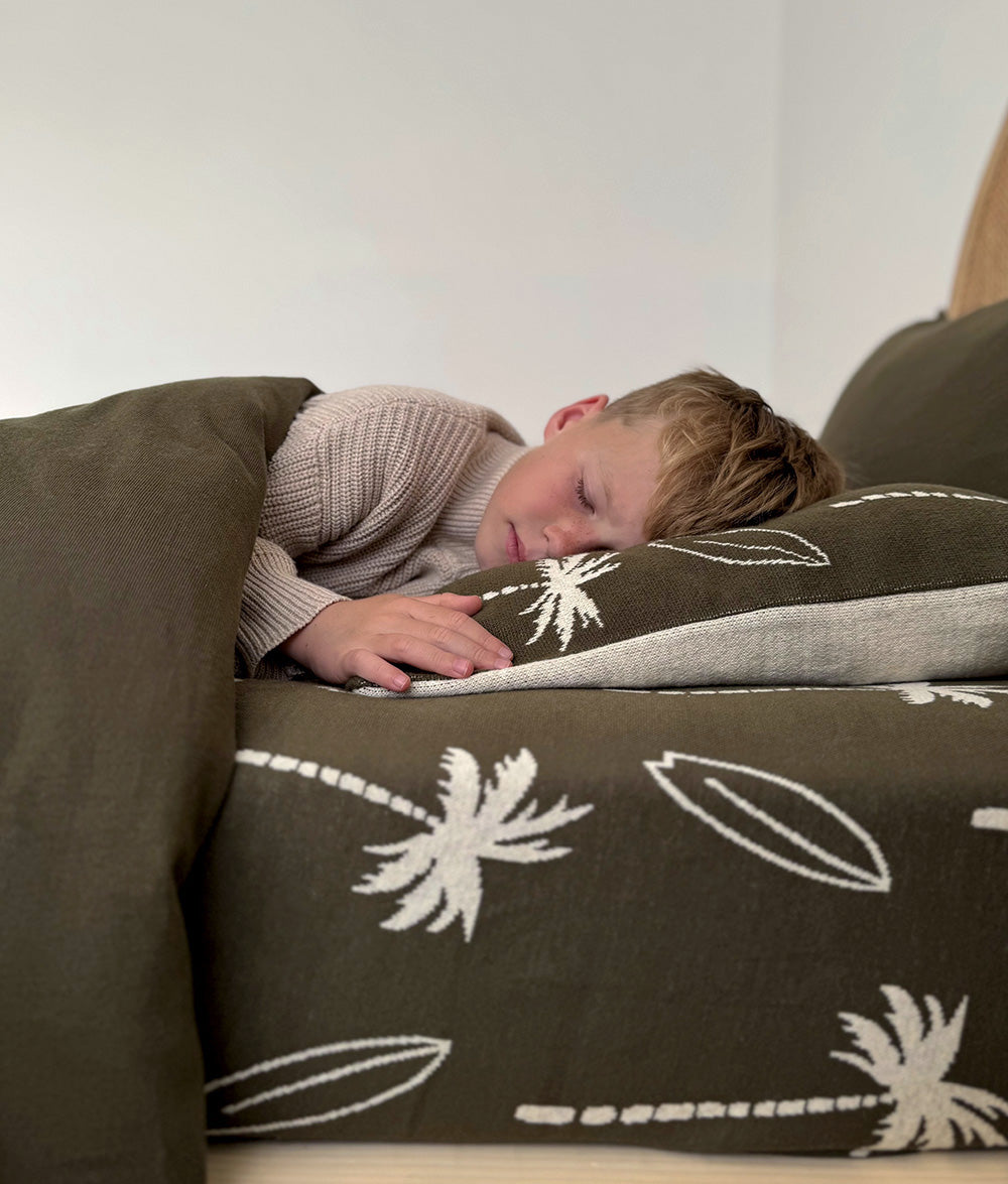 Child sleeping on Olive Surfing Palm jersey cotton fitted sheet.