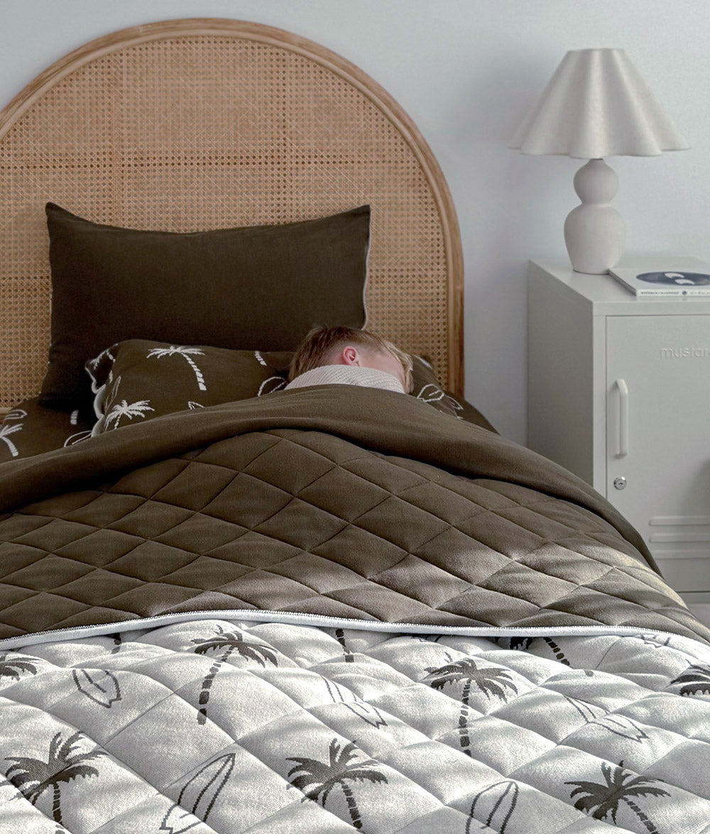 Olive Surfing Palm bedding styled on a single bed with quilt folded over.