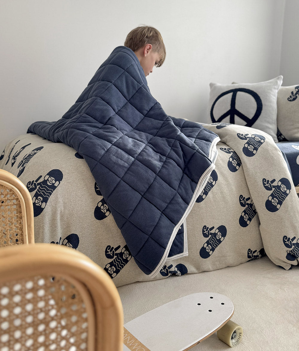 Child wrapped in the Tidal Blue quilt with Skater Life bedding.