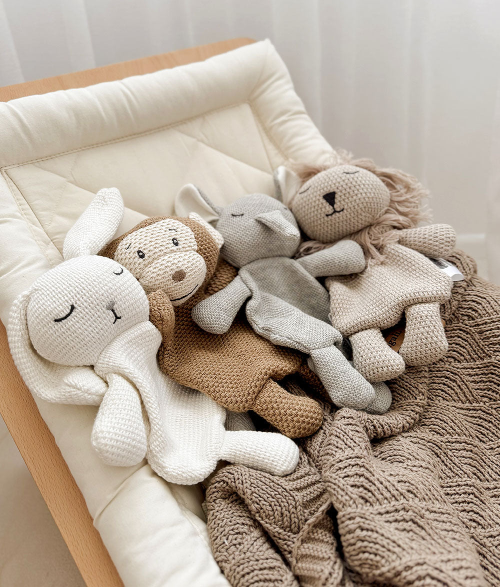 Knitted animal toys on a cushion with a textured blanket