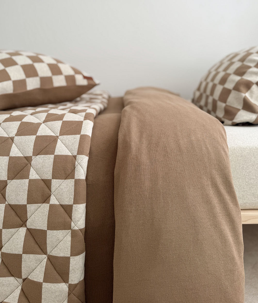 Reversible quilt folded back to reveal the plain ivory reverse.