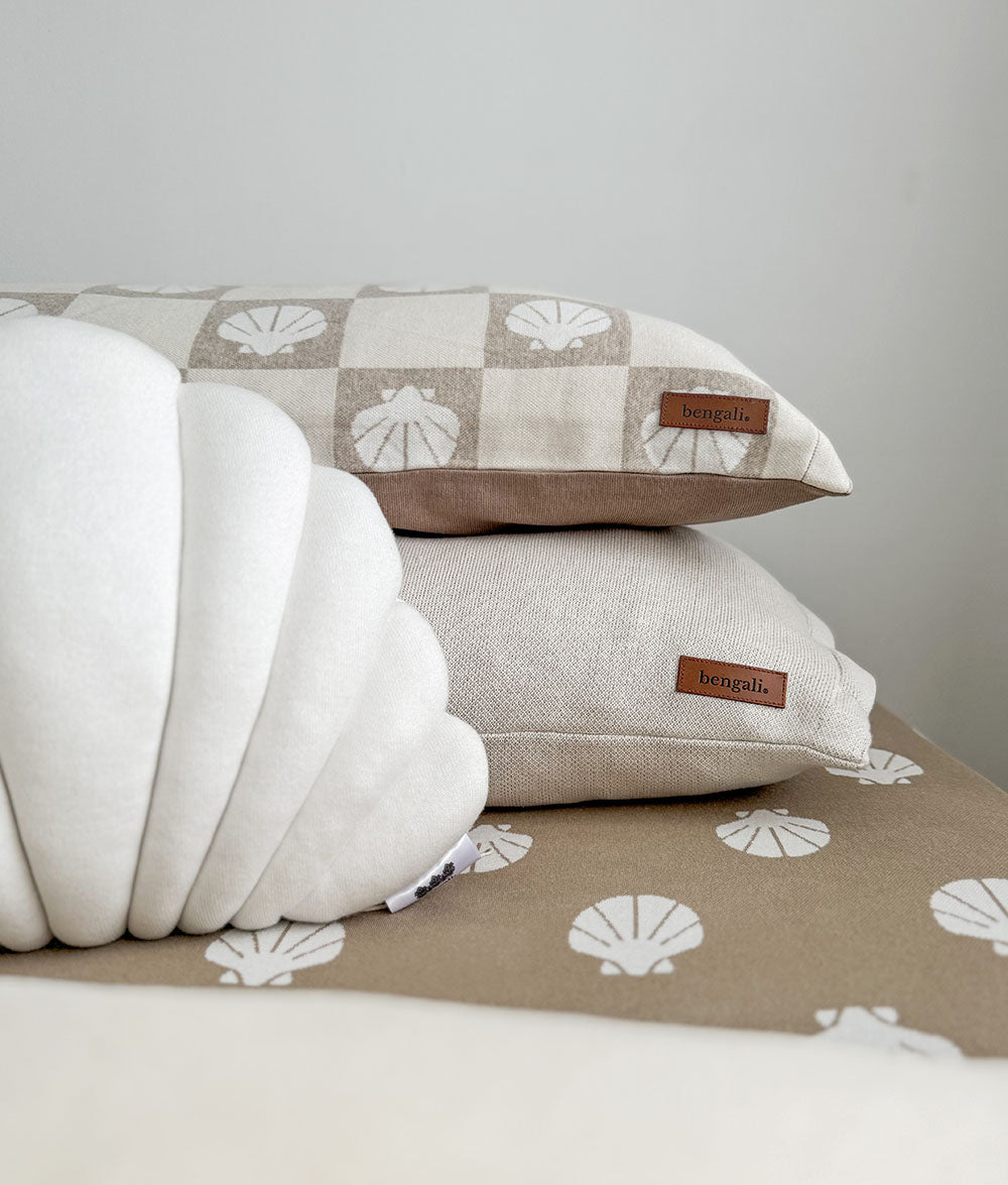 Stack of pillows with shell pattern on a neutral background